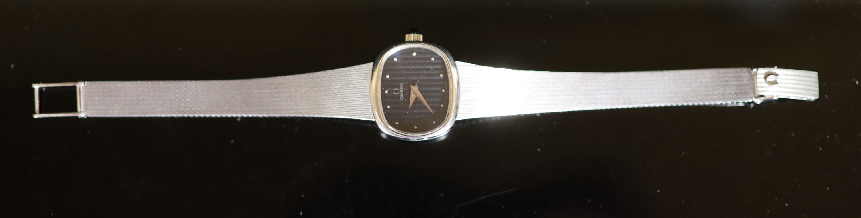 A lady's modern 9ct white gold Omega manual wind wrist watch, on an integral Omega 9ct white gold bracelet